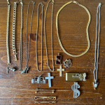 Collection of vintage high school jewelry spread across a wooden nightstand